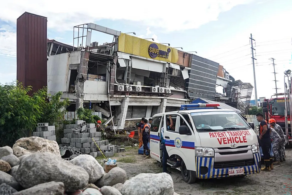 Patient transport vehicle and responders outside earthquake-damaged building